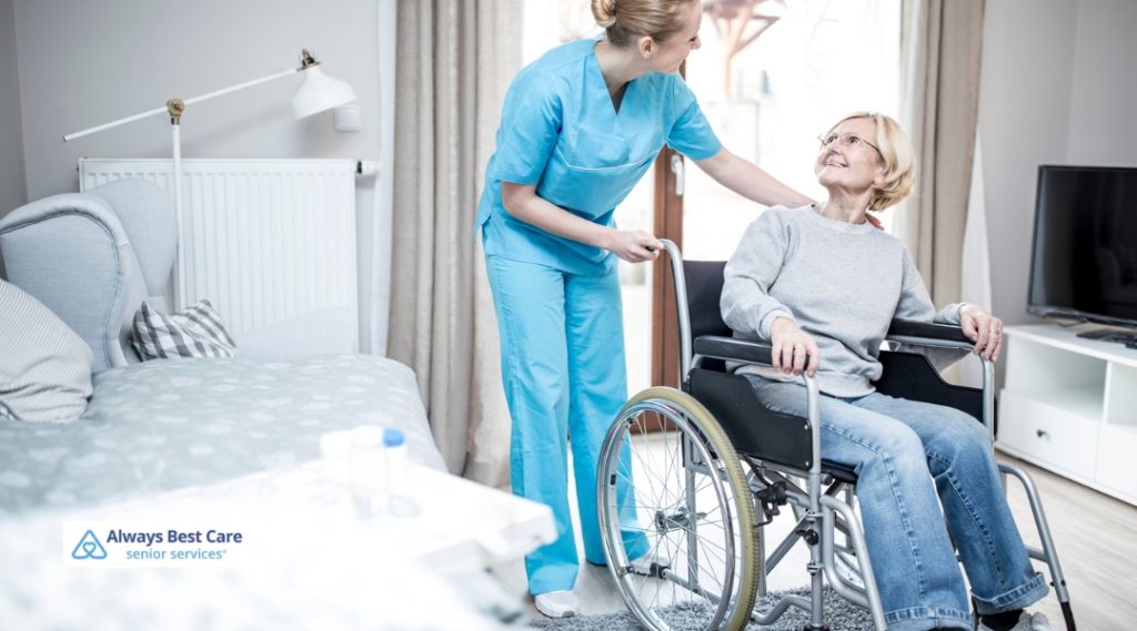 A caregiver assists a senior woman in a wheelchair with a smile, ensuring her comfort and well-being in a well-lit indoor setting.