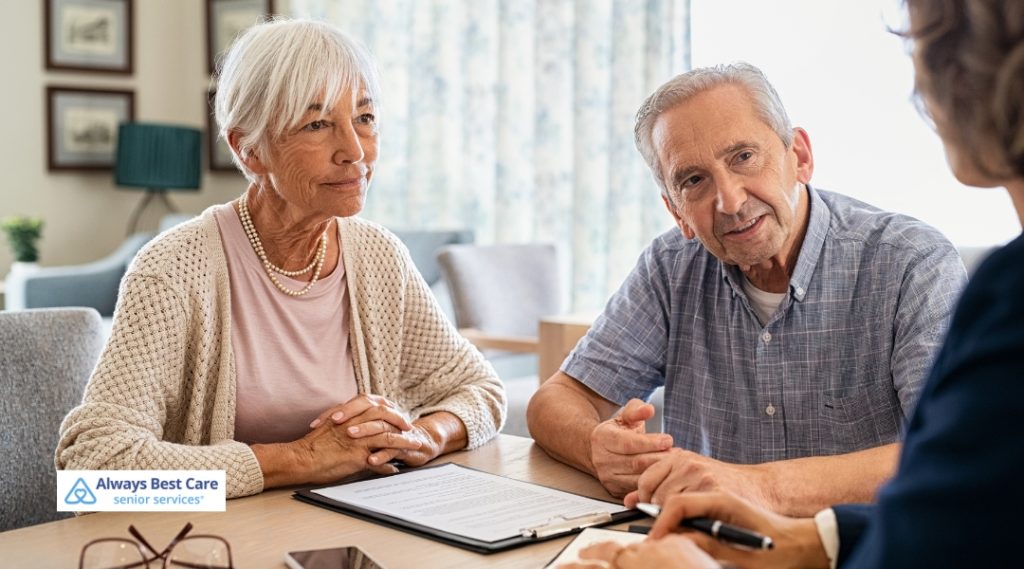 Senior couple engaged in a thoughtful conversation with a care advisor, reviewing documents during a senior care consultation with Always Best Care.
