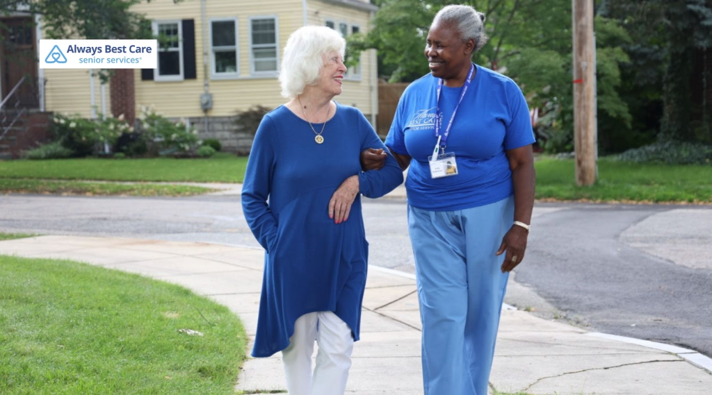 senior walking next to a caregiver.