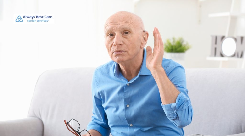 <strong>Kind Conversations: Bringing Up Hearing Loss with Someone You Love</strong> 3 Posts A senior man is sitting on a couch, raising his hand with a questioning expression, as if having trouble hearing or understanding.