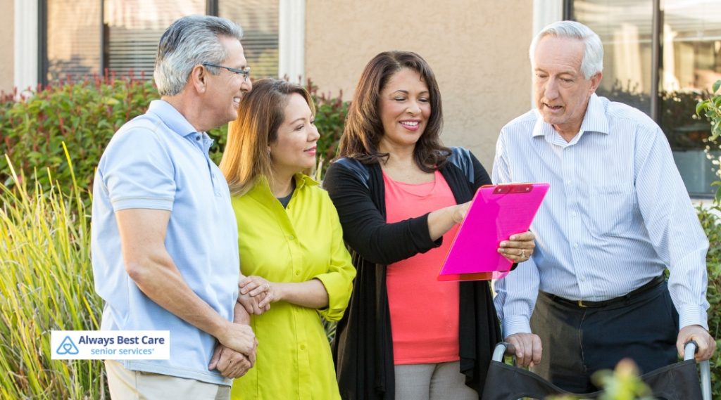 <strong>Unlocking Independence: Advocating for Wise Choices Among Kitchener’s Seniors</strong> 6 Posts A group of four people, two seniors and two family members, standing together outside, discussing paperwork with a sense of community. The Always Best Care logo is in the bottom left corner.