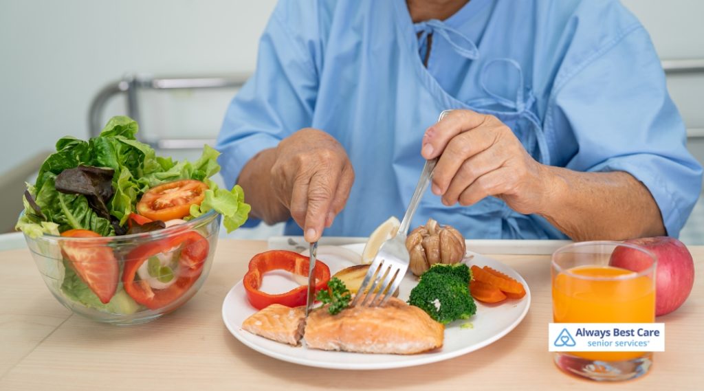 Encouraging Healthy Eating: How to Boost Your Senior’s Appetite in Oakville, ON 3 Posts A senior man in a hospital gown enjoys a nutritious meal with salmon, vegetables, and juice, emphasizing balanced senior diets.