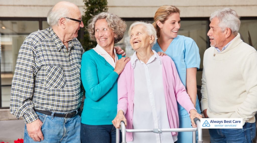 Group of happy seniors interacting with a caregiver, representing social engagement and emotional support in a companion care setting.