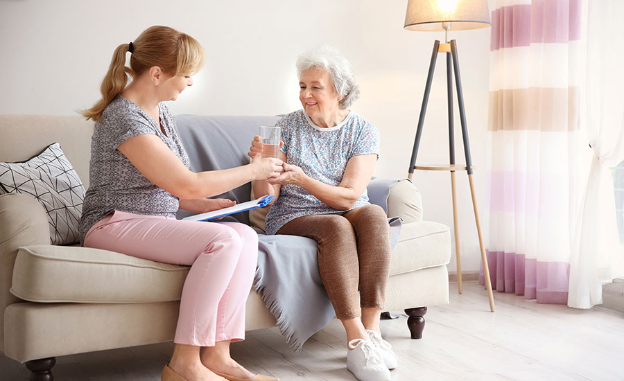  A caregiver giving a glass of water to a senior​